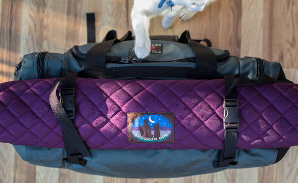 The Road Buddy Lash Straps holding a rolled Skookum Dog Camp Mat on a Road Buddy Duffel 60.